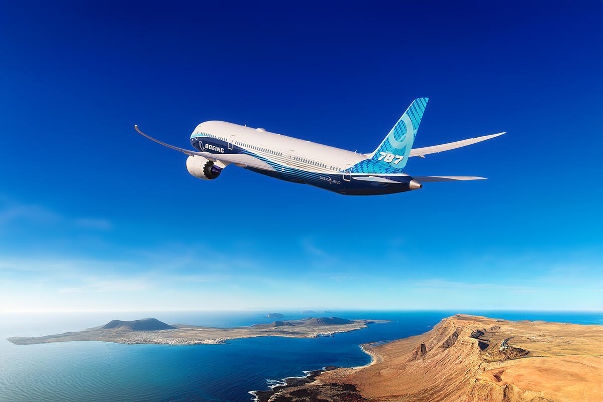A Boeing 787 in flight over ocean and desert